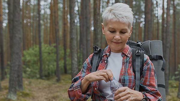 Older woman hiking with back pack in the forest
